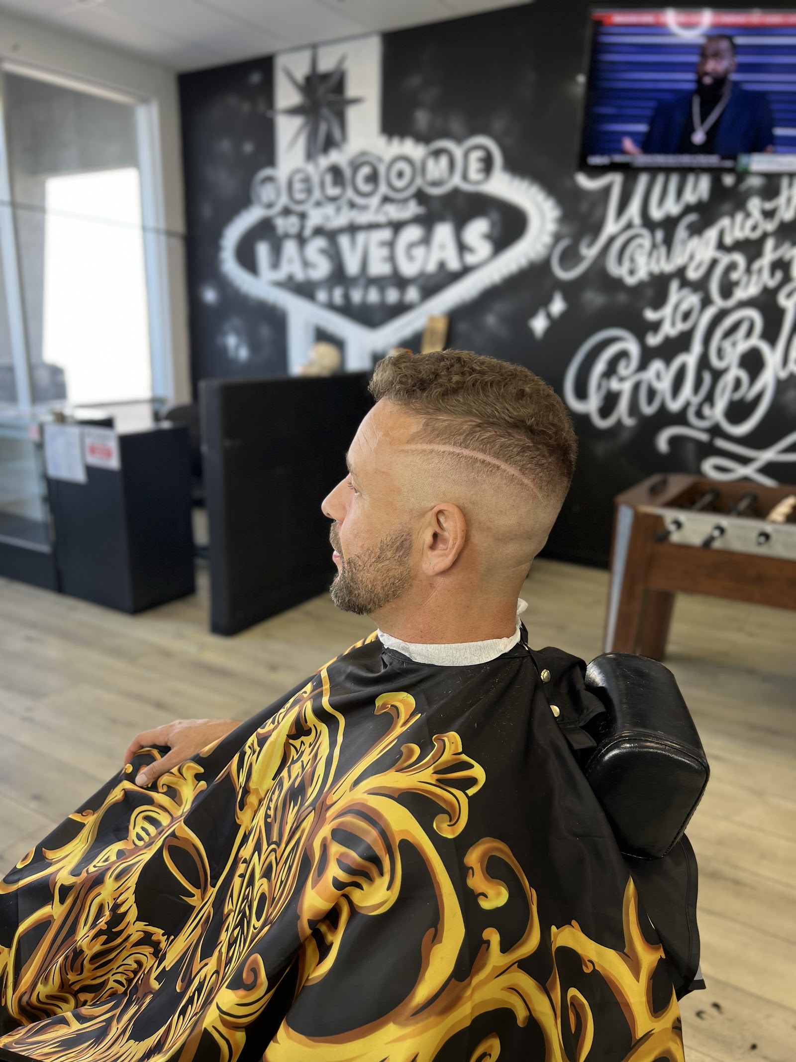 Client with a curly top fade and shaved line design in the barbershop interior