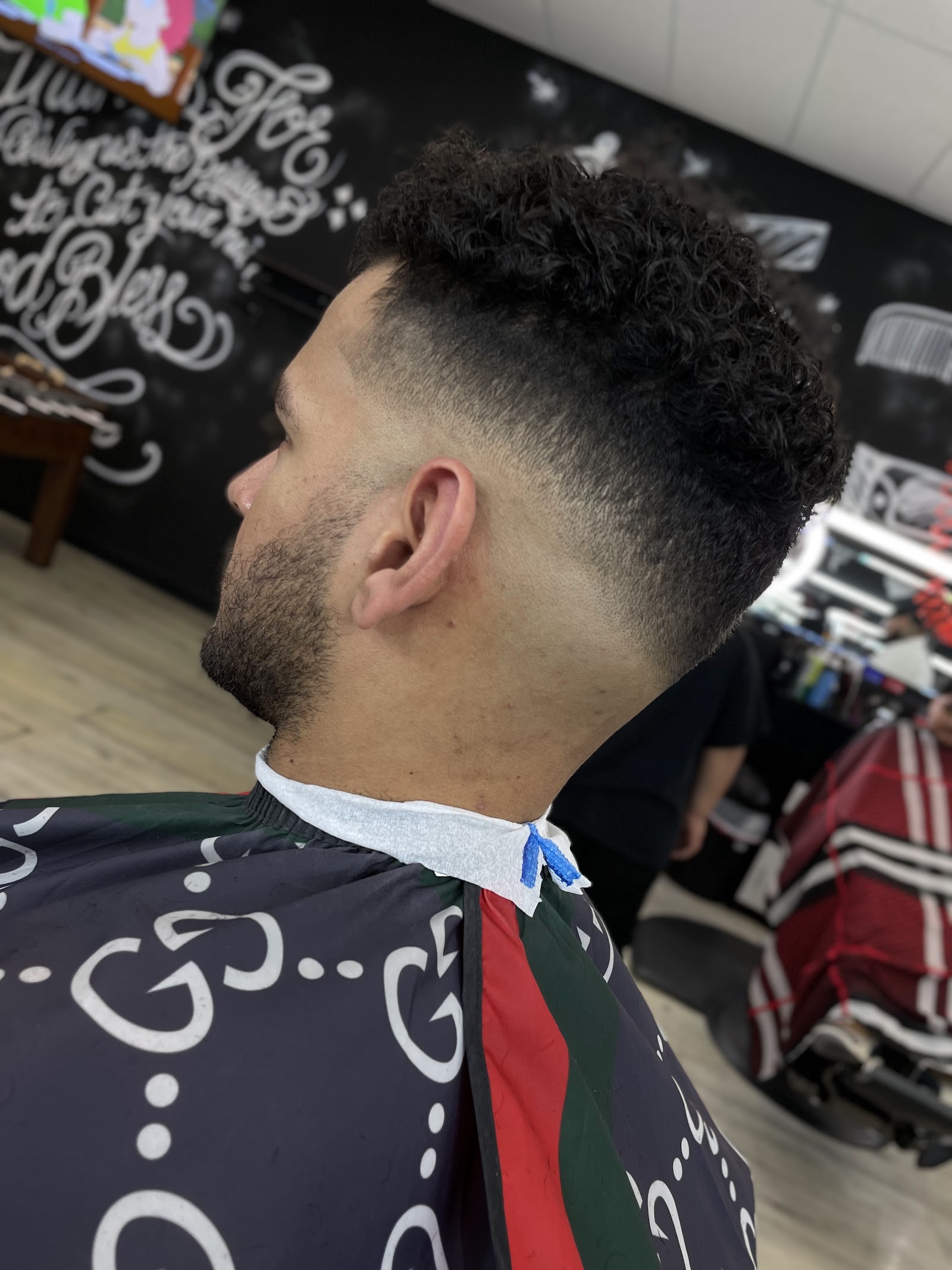 Side profile of a client with a curly top and skin fade